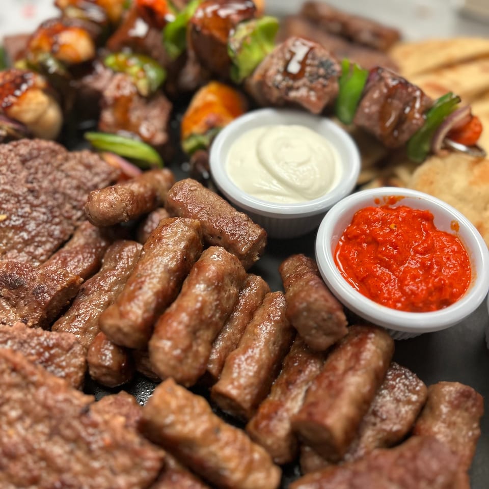 Tito's Lounge grilled meat platter with cevapi, shish kebabs, pita, and two dipping sauces.