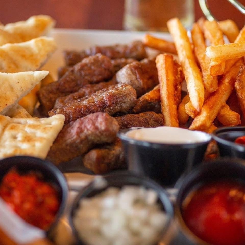 Tito's Lounge cevapi with fries, pita bread, and three dipping sauces.