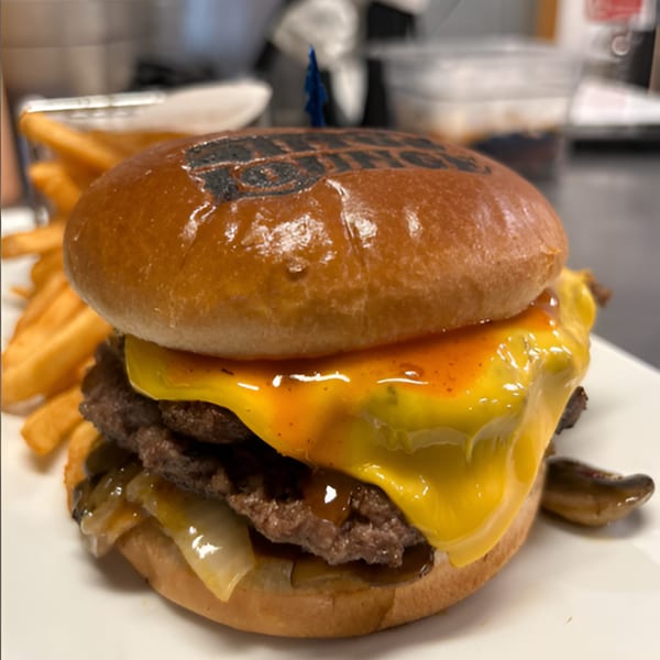 A Tito's Lounge double cheeseburger with melted cheese, sauce, and onions, served with fries.