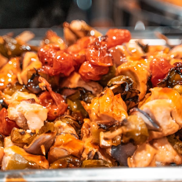 Close-up of Tito's Lounge chicken and vegetable skewers with cherry tomatoes and peppers.