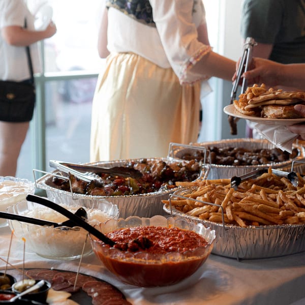 People serving themselves from a buffet of fries, grilled meats, and sauces at Tito's Lounge.